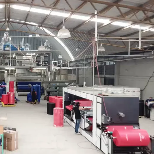 Operario junto a rollos rojos de tela en la planta